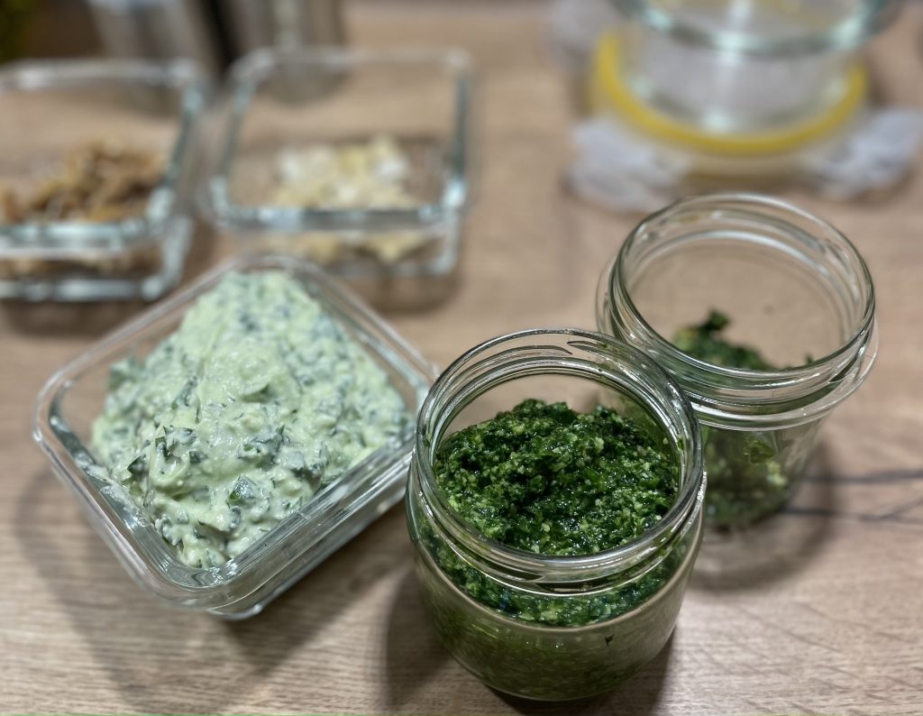 Hellgrüne Fetacreme und dunkelgrünes Pesto aus Bärlauch in Gläsern.